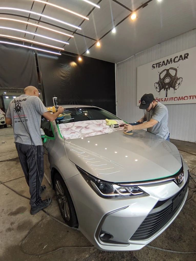Equipe da oficina trabalhando no acabamento de um Corolla prata